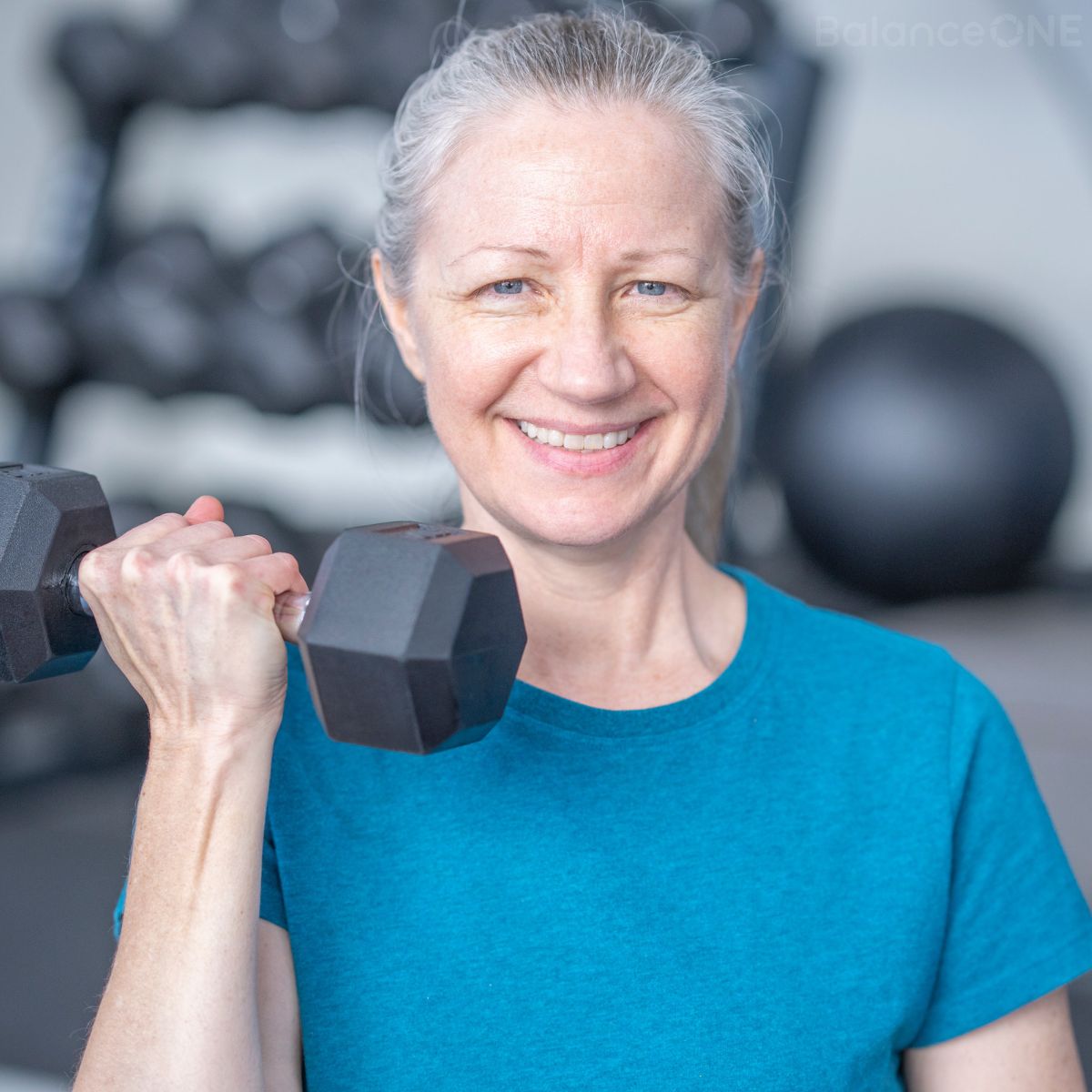 Older woman smiling while lifting a dumbbell